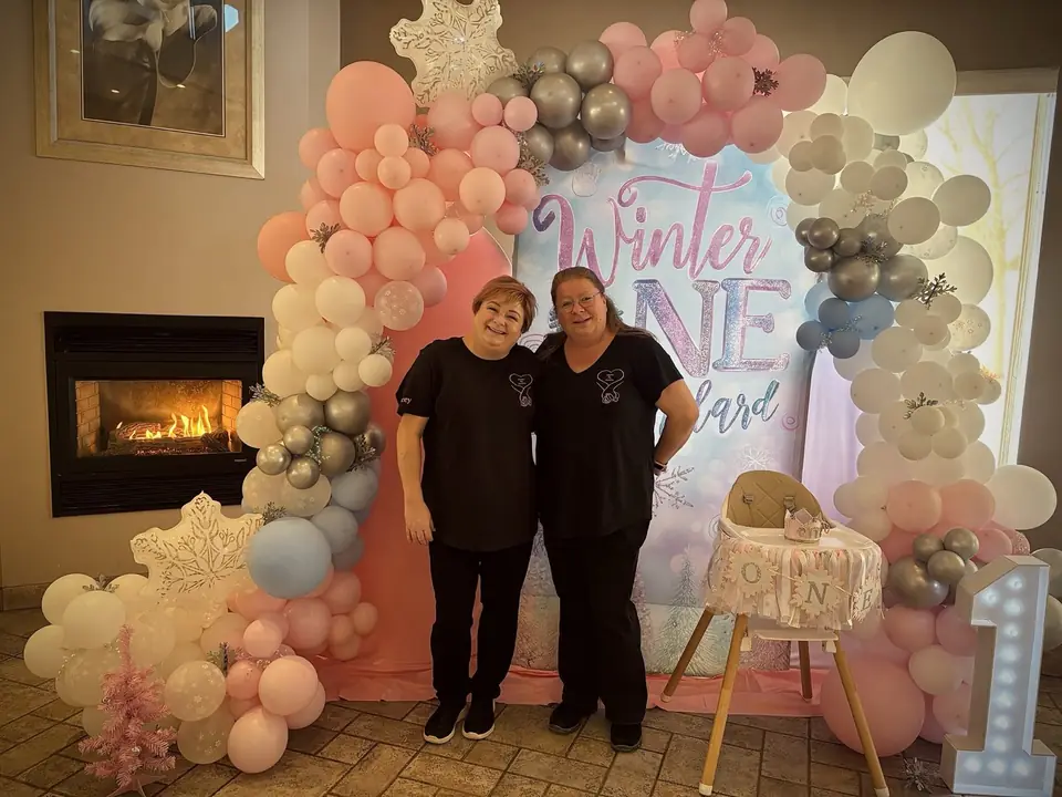 Tracey and Cindy in front of a Winter ONEderland balloon garland and backdrop