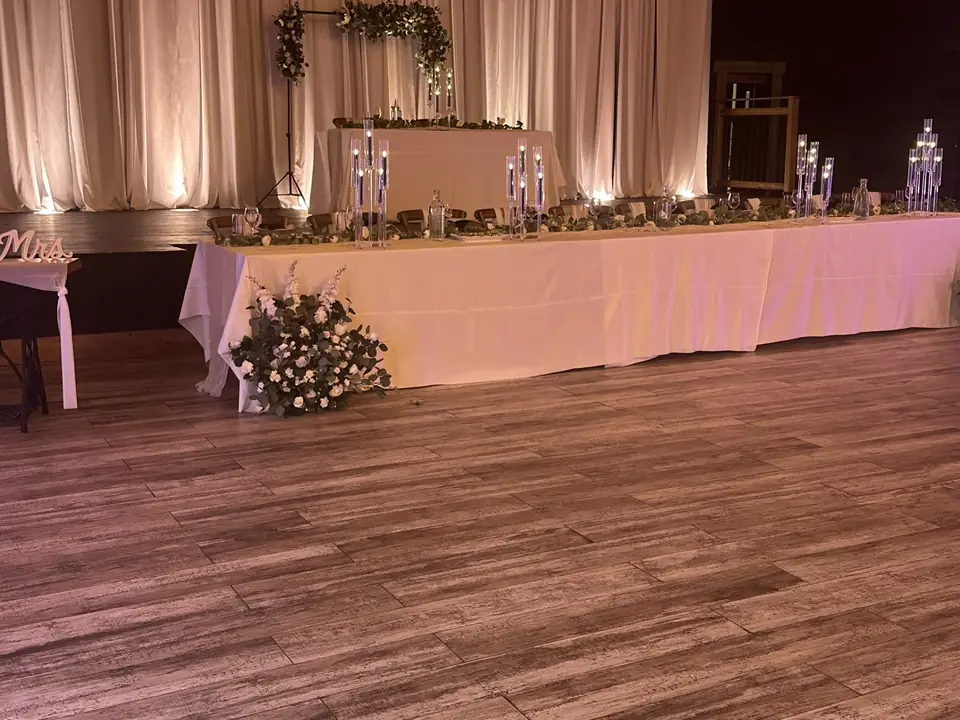 Long head table with crystal candelabras and eucalyptus in front of ivory drapes